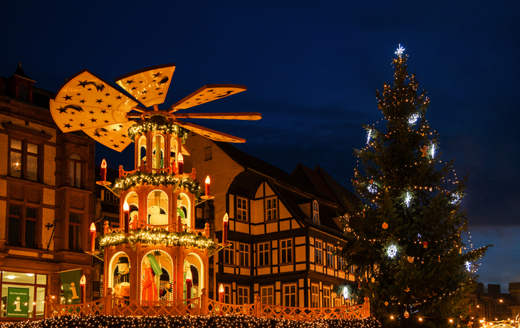 Weihnachtspyramide und beleuchteter Baum vor Fachwerkhaus im Abendlicht
