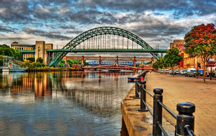 Brücken über den Fluss Tyne in Newcastle bei dramatischem Himmel, Häuser und Verkehr sichtbar.