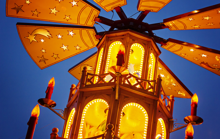 Weihnachtspyramide mit Kerzen und Sternen bei Dämmerung.