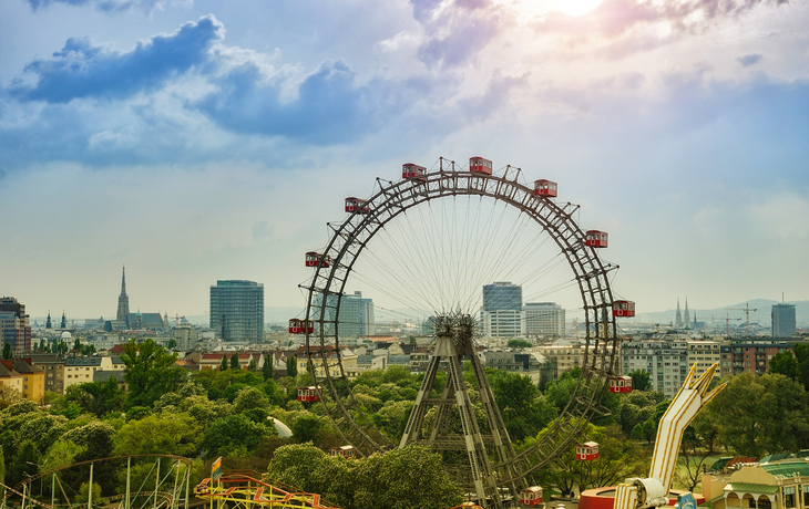 Wiener Riesenrad im Praterpark vor Stadtpanorama und Himmel.
