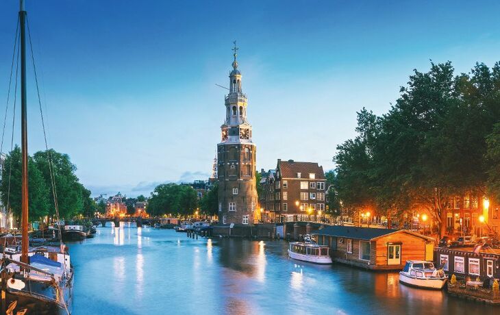 Montelbaanstoren in Amsterdam bei Dämmerung, mit Kanälen und Hausbooten.