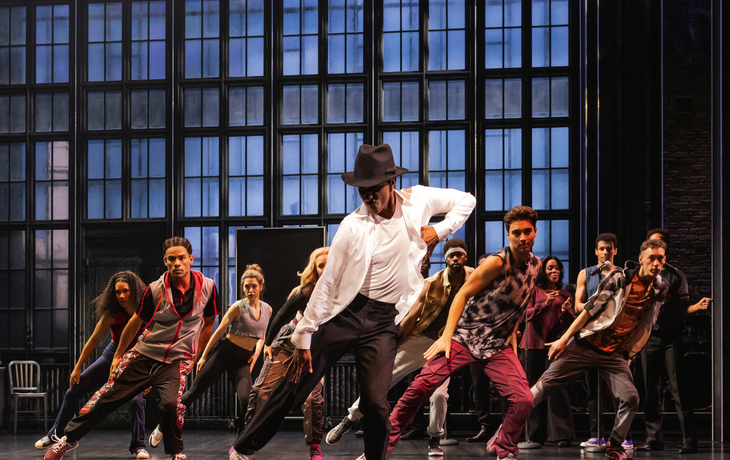 MJ - Das Michael Jackson Musical© Matthew Murphy Tänzer in dynamischer Choreografie auf einer Bühne mit großen Fenstern im Hintergrund.
