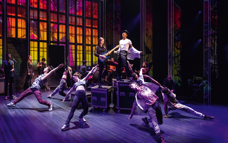 MJ - Das Michael Jackson Musical© Matthew Murphy Tanzgruppe auf Bühne mit farbigem Bühnenbild im Hintergrund.