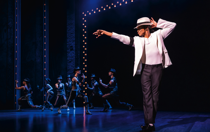 MJ - Das Michael Jackson Musical© Matthew Murphy Tänzer auf Bühne in weißen Anzügen, blauer Hintergrundbeleuchtung.