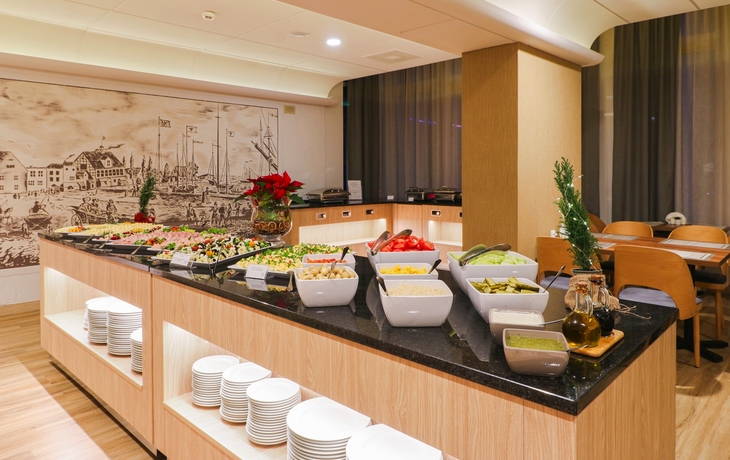 Buffet-Tisch mit verschiedenen Speisen und Schalen in einem hellen Raum.