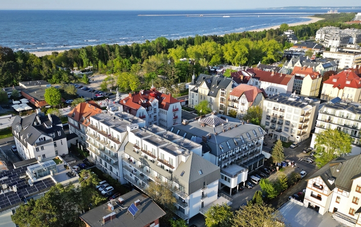 Küstenort aus der Vogelperspektive mit Gebäuden und Meer im Hintergrund.