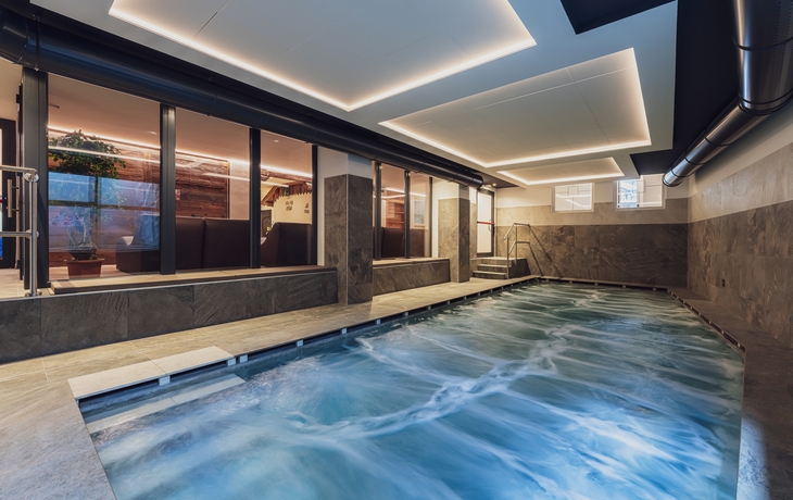 Innenpoolbereich in modernem Hotel mit großen Fenstern und stilvoller Beleuchtung