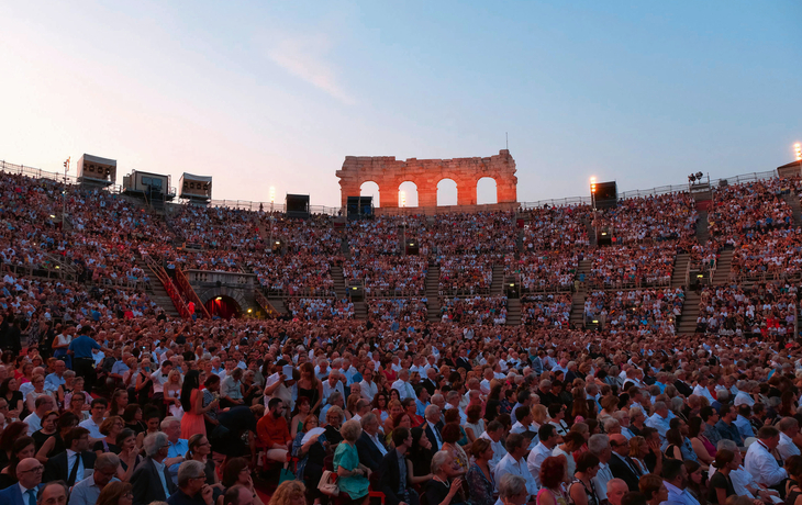 Arena di VeronaCourtesy of Fondazione Arena di Verona © Ennevi Menschenmenge in antikem Amphitheater bei Sonnenuntergang.