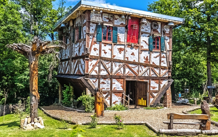 Auf dem Kopf stehendes Fachwerkhaus, umgeben von Bäumen, im Hexentanzplatz Thale.