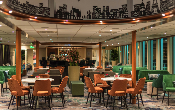 Eleganter Salon mit Bar, Tischen, Stühlen und dekorativen Elementen.