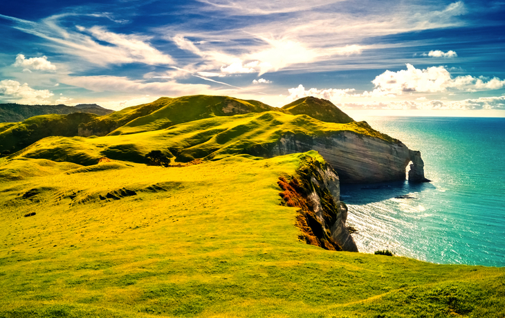 Irlands Küste mit Klippen und tiefblauem Meer unter einem bewölkten Himmel.