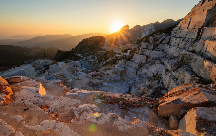 Sonnenuntergang über einem Marmorsteinbruch mit Blick auf die umliegenden Berge und Täler.