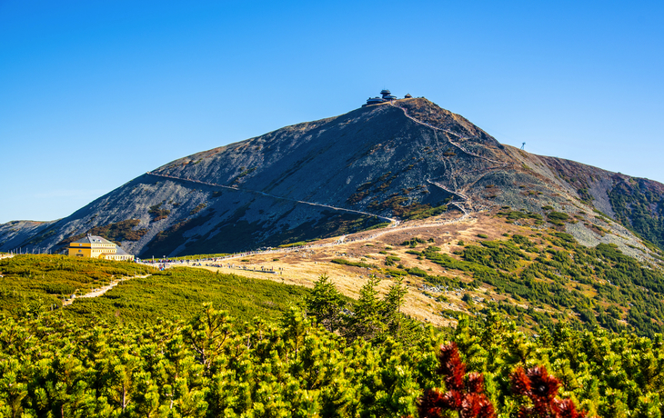Die Schneekoppe im Riesengebirge bei klarem Himmel und herbstlicher Vegetation.