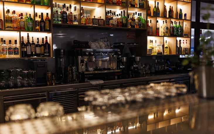 Bar im Hotel mit Gläsern und beleuchteten Flaschenregalen