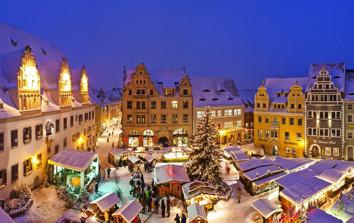 Verschneiter Weihnachtsmarkt in Meißen an der Elbe bei Nacht.