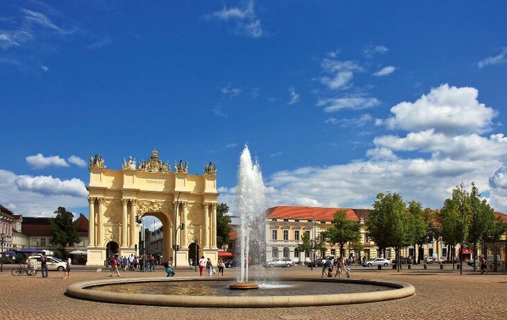 Brandenburger Tor in Potsdam mit Brunnen und blauem Himmel.