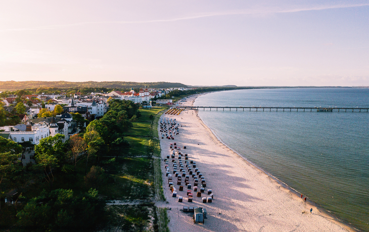 Strand mit Strandkörben, Küstenort und Seebrücke aus der Vogelperspektive.