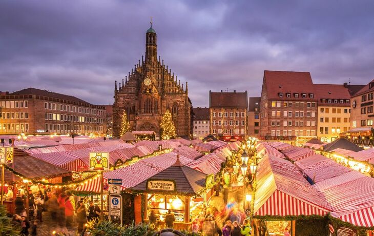 Weihnachtsmarkt mit Kirche im Hintergrund bei Abenddämmerung