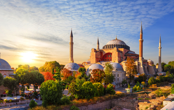 Hagia Sophia in Istanbul bei Sonnenuntergang, umgeben von Bäumen und alten Gebäuden.