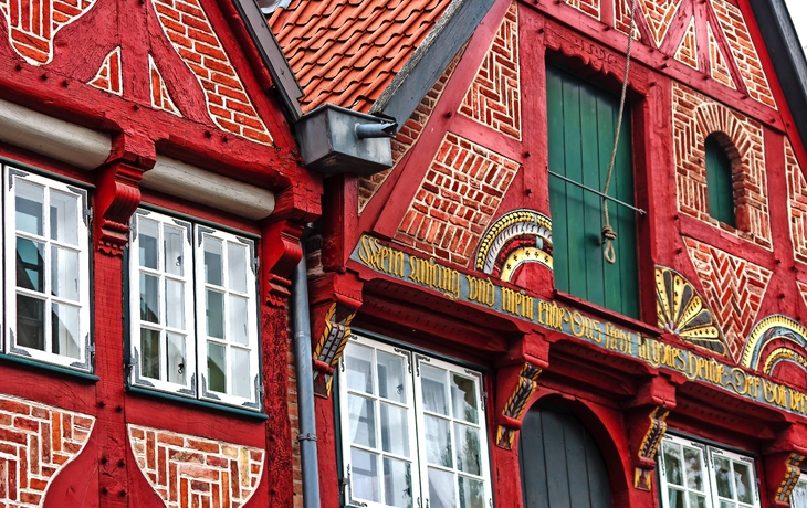 Rotes Fachwerkhaus mit verzierten Fenstern und Holzarbeiten.