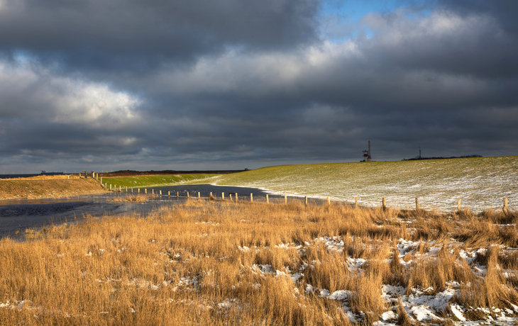 Landschaft mit schneebedecktem Feld und bewölktem Himmel.