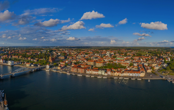 Luftaufnahme einer Küstenstadt mit Hafen und historischer Architektur.