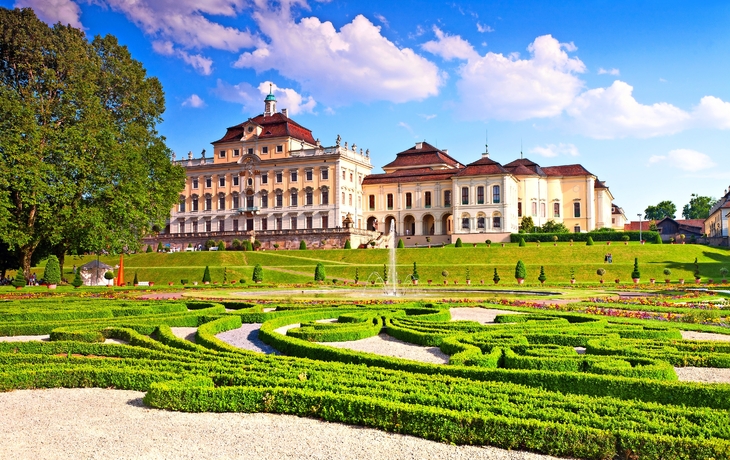 Historisches Schloss mit Garten bei sonnigem Himmel.