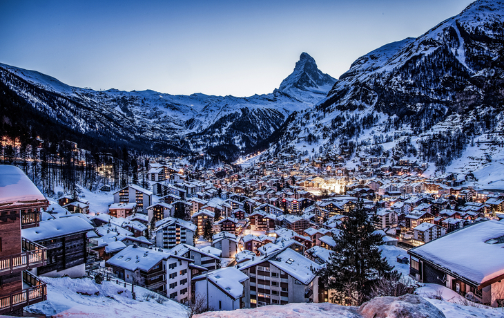 Verschneite Berglandschaft mit Dorf im Abendlicht, Matterhorn im Hintergrund.