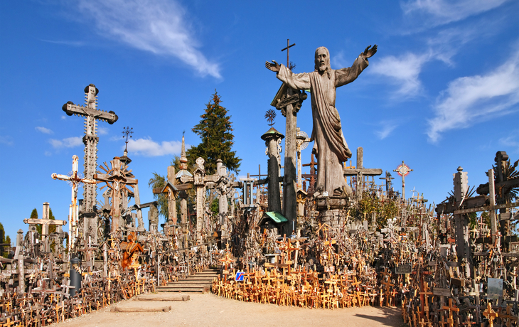Viele Kreuze auf einem Hügel mit einer großen Christusstatue im Zentrum.