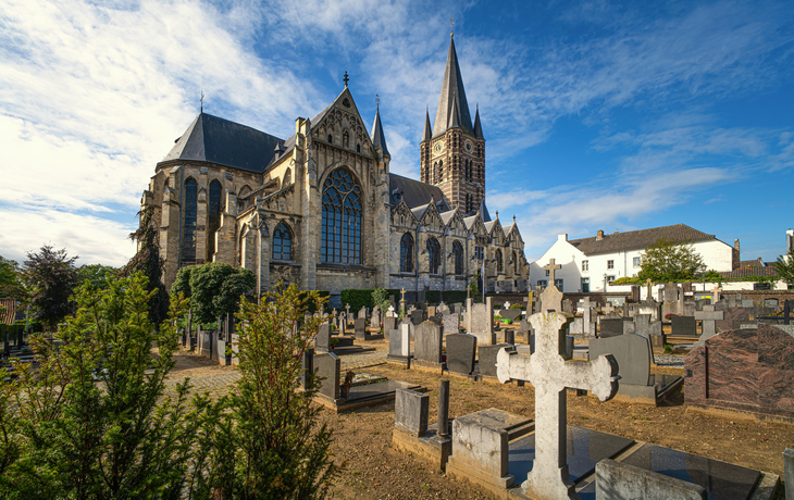 Historische Kirche mit Friedhof im Vordergrund bei blauem Himmel.