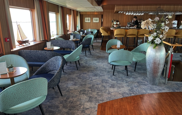 Gemütliche Lounge-Bar mit Tischen, Stühlen und Dekoration.