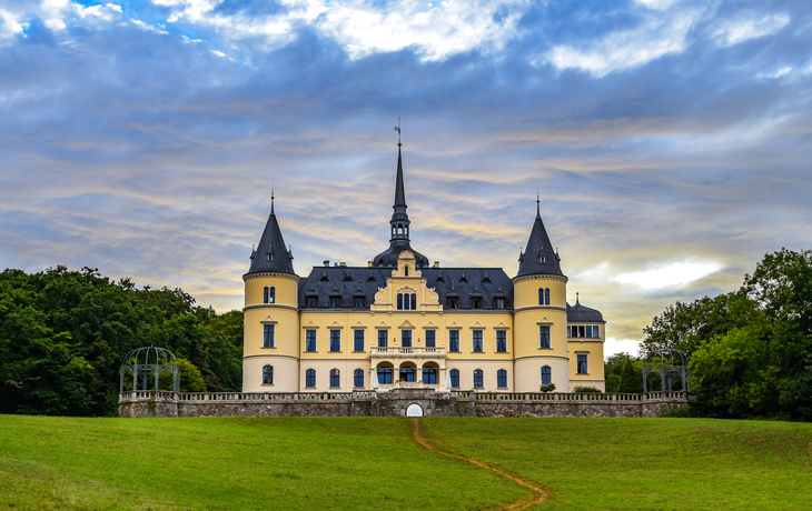 Schloss Ralswiek auf Rügen vor bedecktem Himmel und grüner Wiese