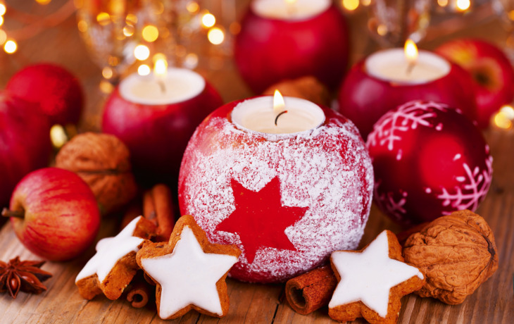 Weihnachtliche Deko mit Äpfeln, Kerzen, Zimtstangen und Gebäck.