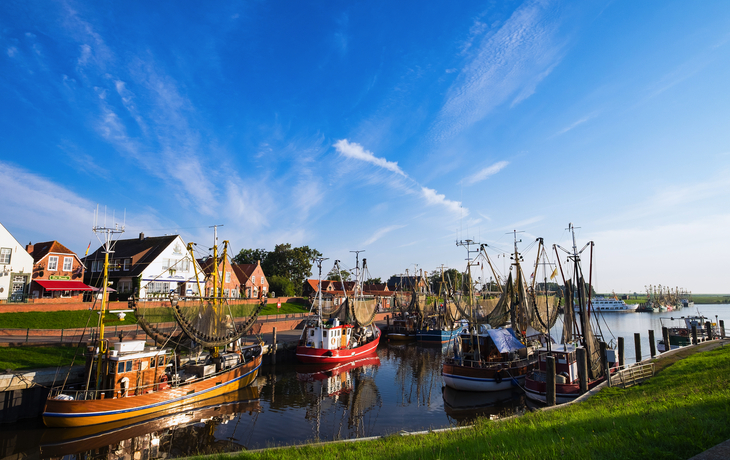 Fischerboote im Hafen von Greetsiel an der Nordseeküste bei sonnigem Wetter.