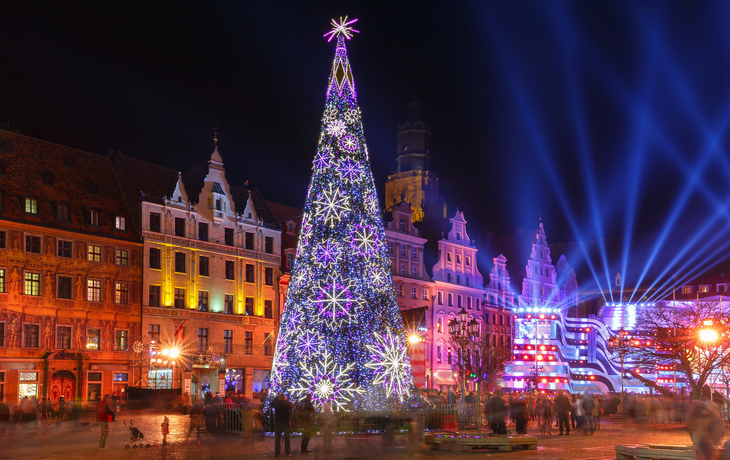 Beleuchteter Weihnachtsbaum auf einem festlichen Marktplatz bei Nacht.