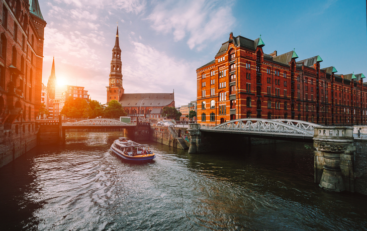 Kanallandschaft mit Brücke und Backsteingebäuden bei Sonnenuntergang.
