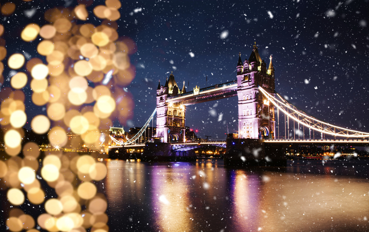 Tower Bridge in London im Schnee zur Weihnachtszeit mit Blick auf die Themse bei Nacht.