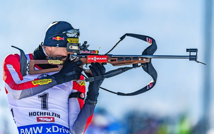 Biathlet zielt mit Gewehr beim Wettkampf in Hochfilzen.