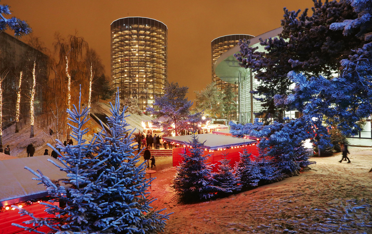 Verschneite Autostadt Wolfsburg mit festlicher Beleuchtung im Winter.