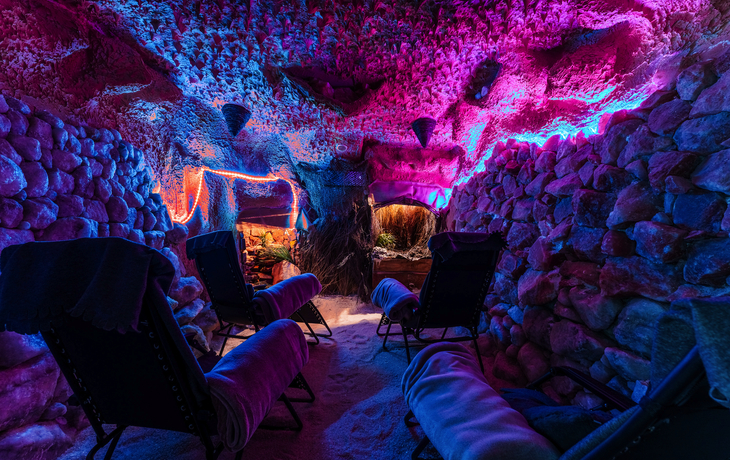 Eine bunt beleuchtete Höhle mit Liegestühlen.