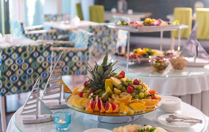 Frühstücksbuffet mit Tisch voller geschnittener Früchte in einem Hotelrestaurant.