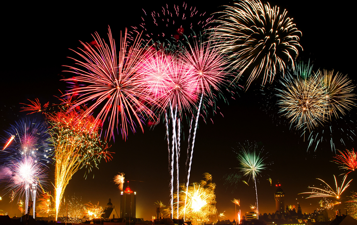 Feuerwerk erhellt den Nachthimmel über einer Stadt.