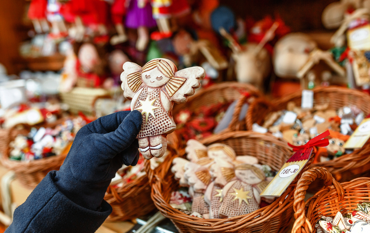 Handgemachter Weihnachtsengel auf einem festlich dekorierten Weihnachtsmarkt im Winter.