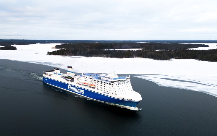 Finnlines-Fähre im winterlichen, vereisten Gewässer mit schneebedeckten Ufern.