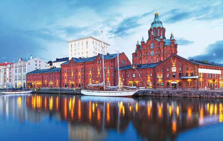 Helsinki abends im Winter, beleuchtete Gebäude am Wasser.