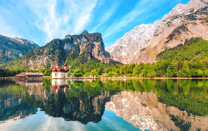 Kirche St. Bartholomä am Königssee in Bayern vor Bergen und Reflektionen im Wasser.