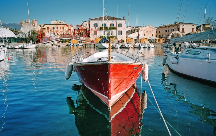 Hafen von Bardolino am Gardasee mit Booten und Gebäuden im Hintergrund.