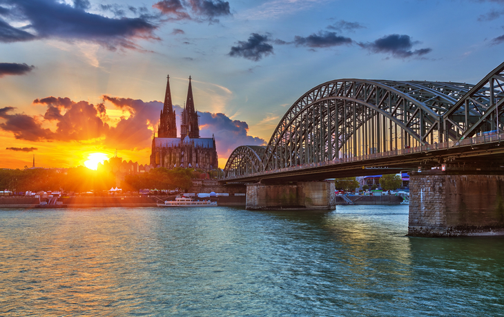 Kölner Dom und Hohenzollernbrücke bei Sonnenuntergang am Rhein.