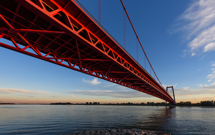 Rote Rheinbrücke in Emmerich bei Sonnenuntergang über dem Fluss.