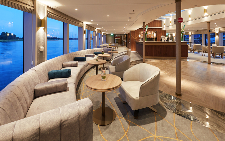 Barlounge mit modernen Möbeln und großen Panoramafenstern auf einem Schiff.